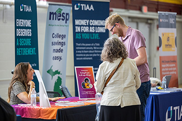 Two people stand in front of an information table for MESP