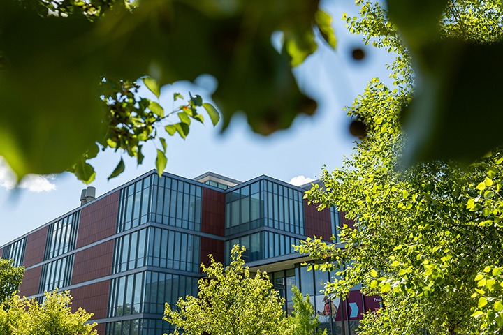The Biosciences building peers through trees in the foreground