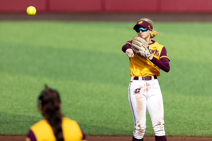 A CMU softball infielder throws a ball across the diamond