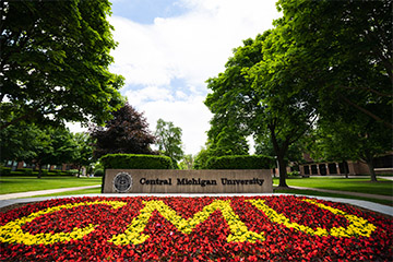 A sign reading Central Michigan University with a flower bed that reads CMU.