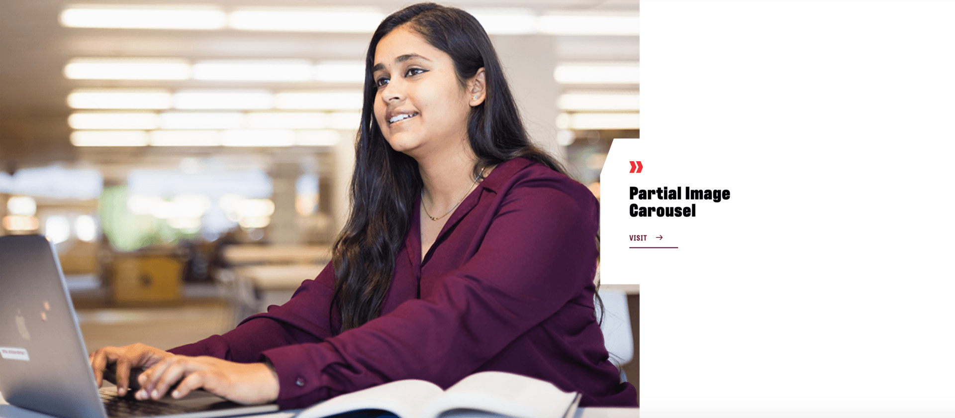 Female student sitting at a laptop with an open textbook.