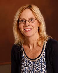 Michelle Bigard wears glasses, a dark sweater and patterned blouse in a professional headshot.