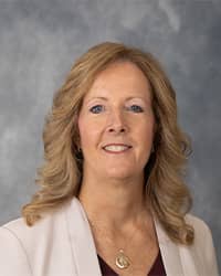 Melissa Hutchinson, Executive Director of Counseling Services profile portrait, wearing white blazer against a grey background.