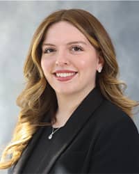 Kyleigh Ayala, Counseling Center Intern Headshot, wearing a black shirt, black blazer and a grey background.