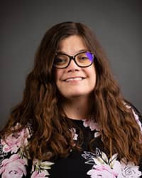 Kate Caszatt, Counseling Center Counselor, wearing a pink and black floral shirt for profile image
