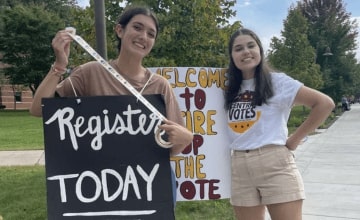Students holding signs and stickers encouraging students to register to vote