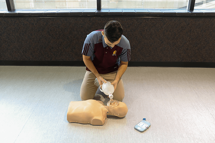 An instructor demonstrates CPR techniques on a mannequin
