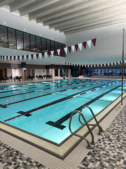 An image of the pool at the Student Activity Center with red and white lane dividers. The pool is lit by underwater lights.