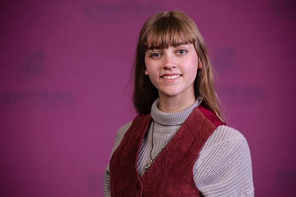 Professional headshot of Morgan Jowett wearing a tan sweater with burgundy vest while looking at the camera.