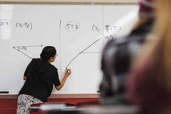 Instructor doing a math problem on a whiteboard