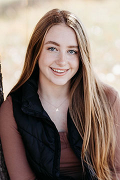 A photo of SI Leader, Addie Followell, posing outdoors and leaning on a tree.