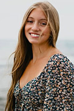 A photo of SI Leader, Carly Ramo, posing outdoors in front of a body of water