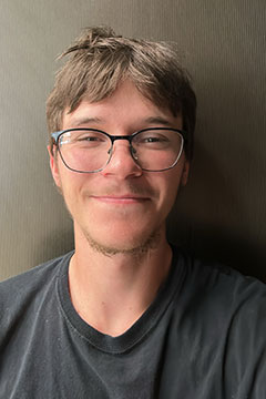 A photo of SI Leader, Conner Ripley, smiling in front of a grey backdro