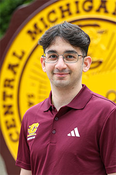 A photo of Supplemental Instruction Assistant Program Supervisor, Joe Wahbeh, in front of the CMU seal on Warriner Mall