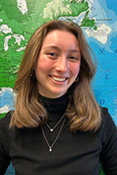 A headshot of SI Leader, Taylor Rinke, posing in front of a world map.