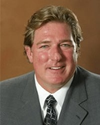 Thomas Lapka is an Alumni Board member who holds Emeritus status and he is wearing a gray suit and dark navy with a square pattern tie and he has blonde hair.