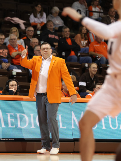 Todd Simon, a CMU graduate, shown coaching in orange jacket and grey pants during a basketball game for Bowling Green.