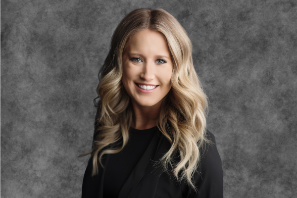 A woman with long blonde hair and a black shirt is smiling.