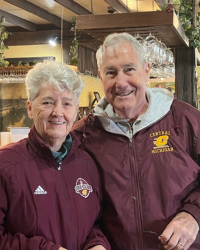 A man and woman wearing maroon jacket. The woman's has an Adidas logo showing and the man's has a Central Michigan logo.