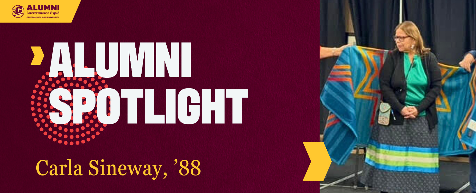 A Central Michigan University Alumni Spotlight graphic featuring Carla Sineway, '88. Carla is wearing a green top and long patterned skirt, standing in front of a blue and gold star quilt being held up behind her.