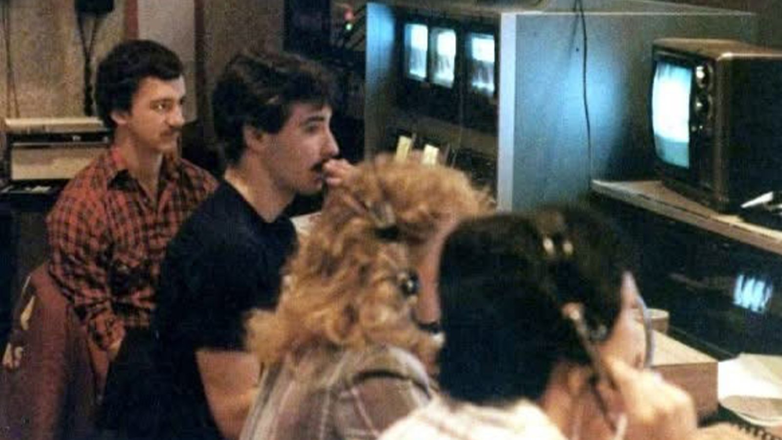 Four students are in a television production booth during a college news broadcast.
