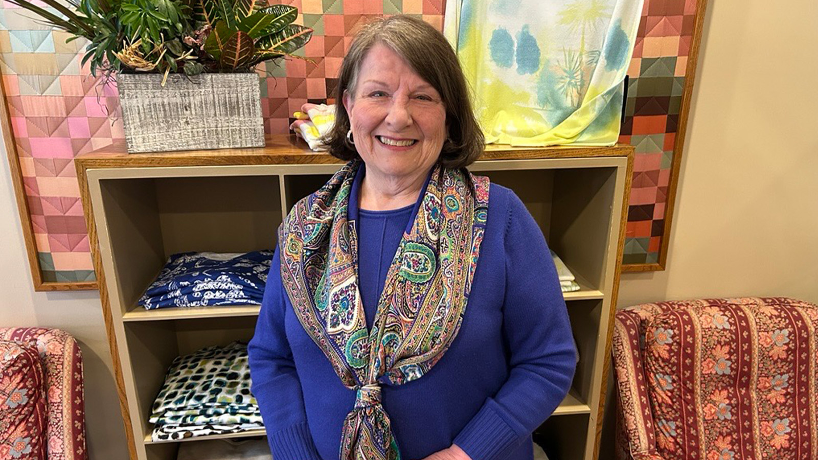 Helen Chase 1600x900 A woman wearing a blue shirt and paisley scarf is smiling.