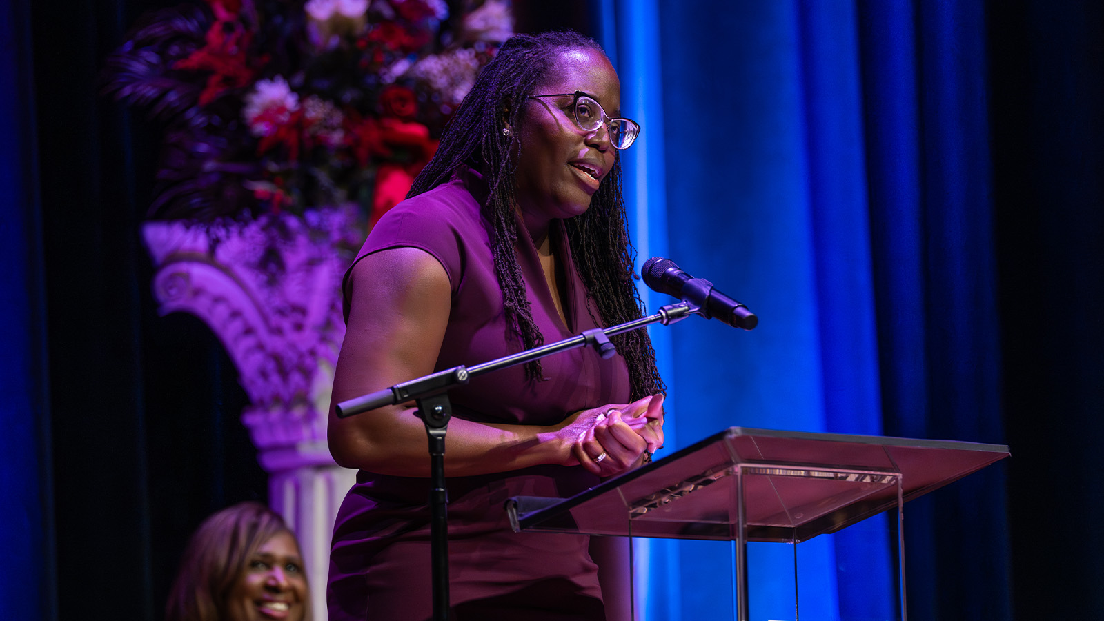 A woman speaks while standing at a podium with a microphone.