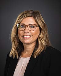 Kristie Miner Kristie Miner wears glasses, a black blazer and light blouse in a professional headshot.